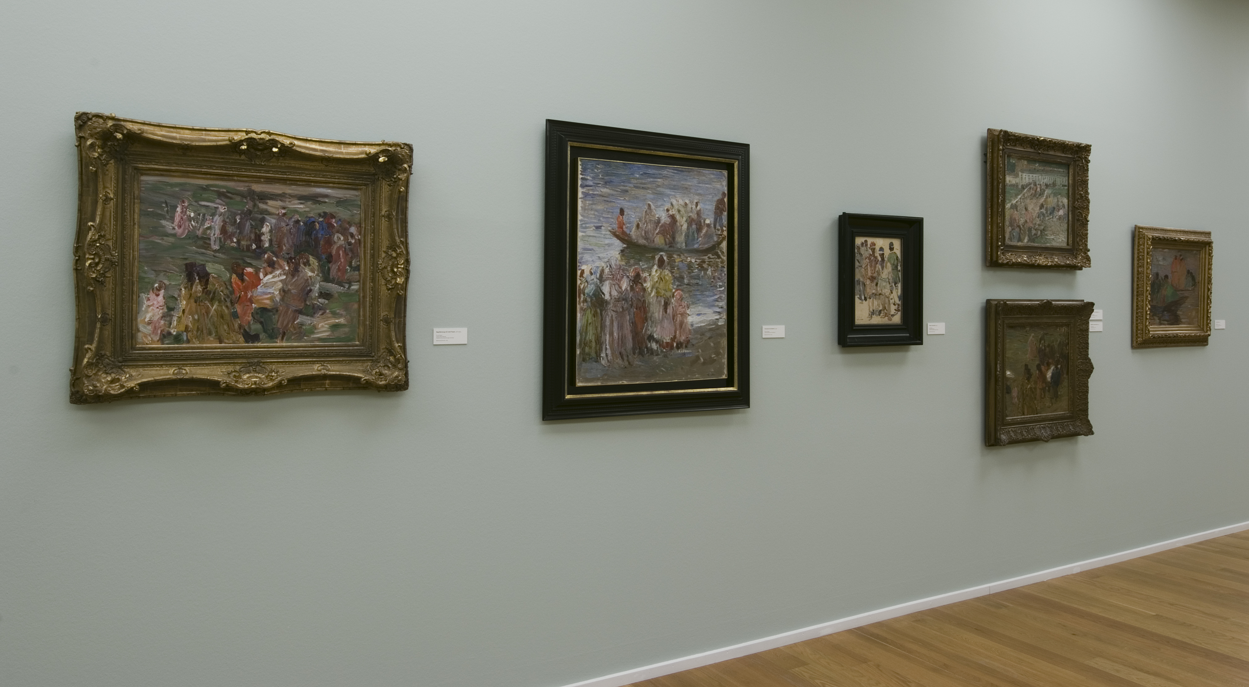 AI generated: The image shows a wall in an art gallery on which several paintings are hung in different frames. The gallery has a wooden floor and softly lit walls.