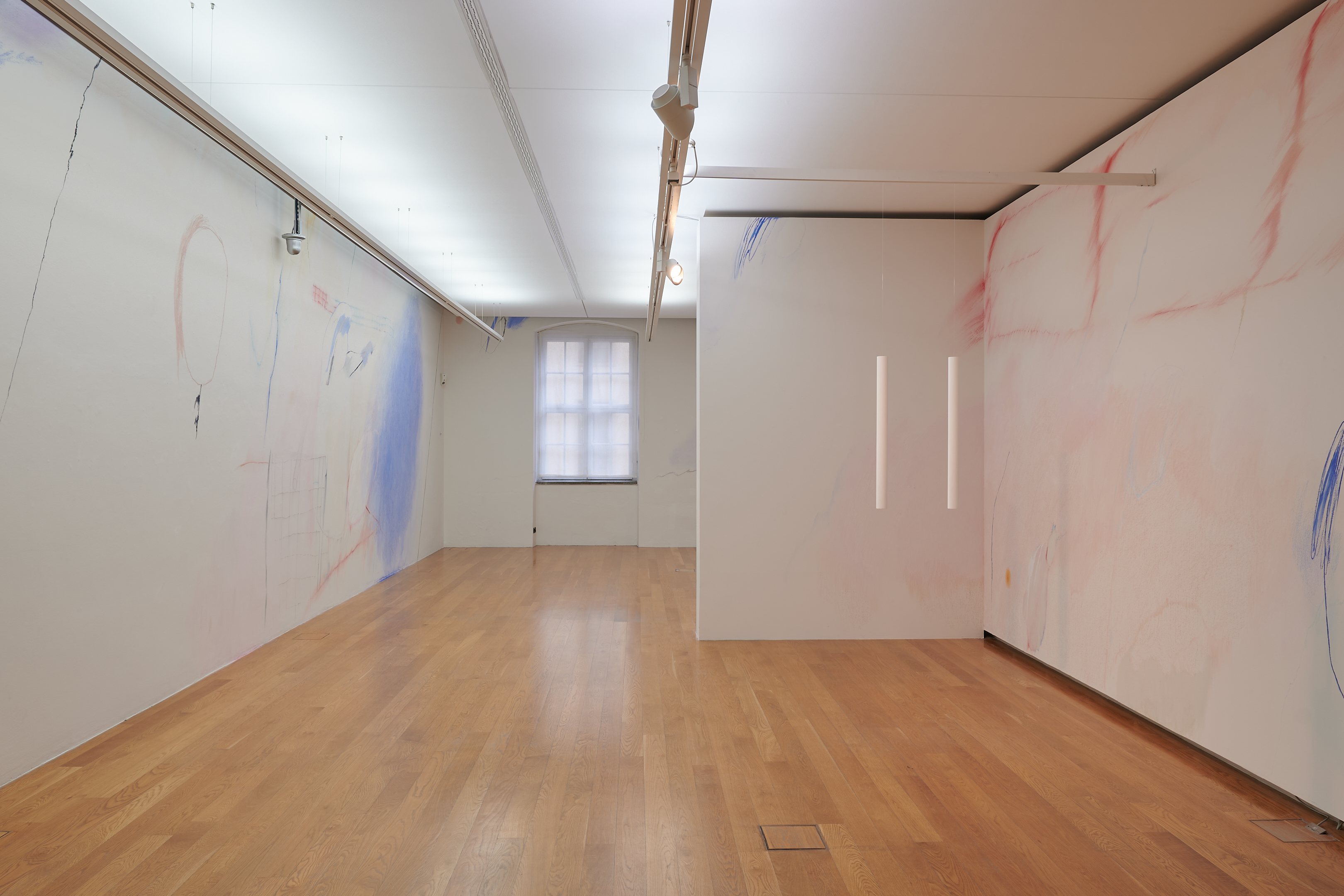AI generated: The main content of the image is a minimalist exhibition space with light-coloured walls on which subtle drawings can be seen. The room has a wooden floor and is equipped with a window front at the end.