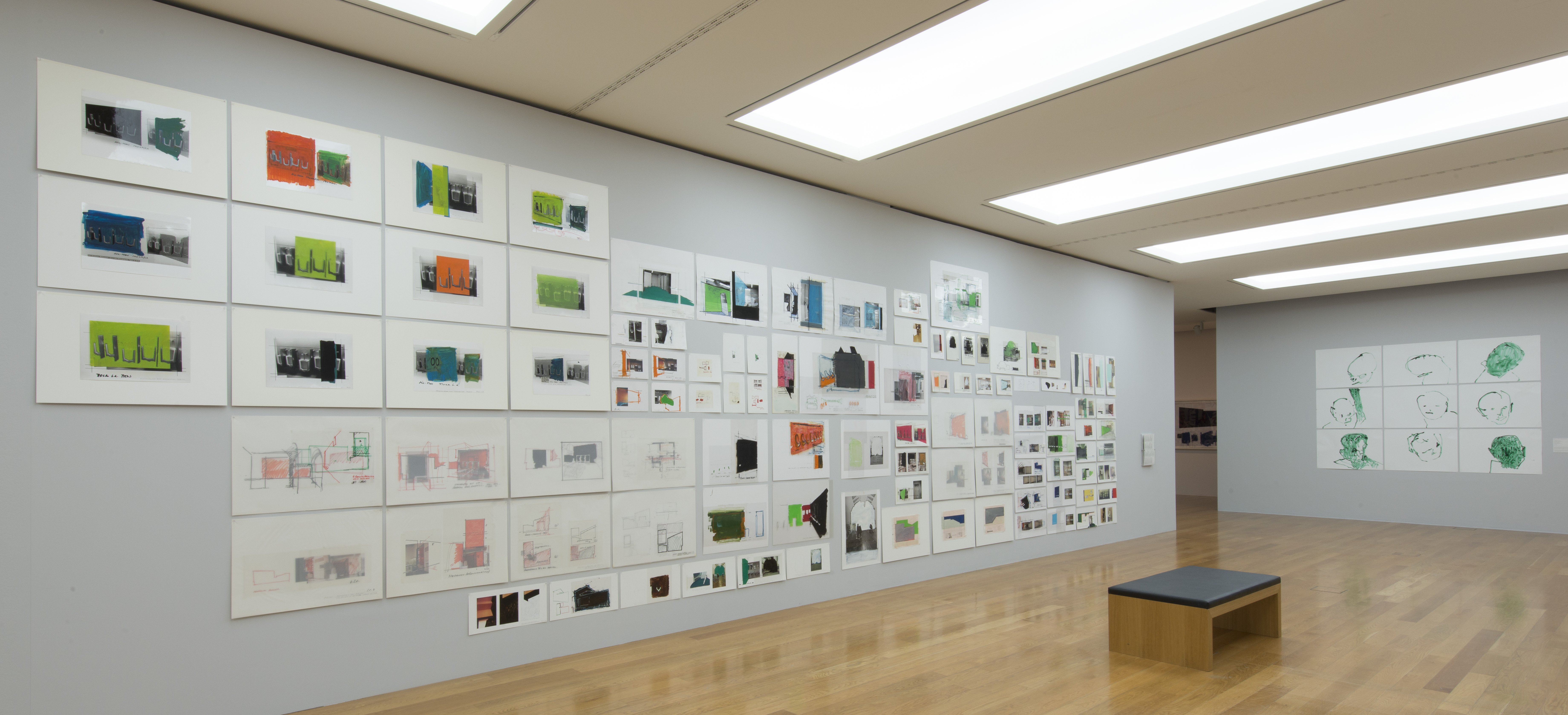 KI generiert: Ein Galerieraum zeigt eine Vielzahl von gerahmten Kunstwerken, die in mehreren Reihen an der Wand angebracht sind. Die Malereien und Zeichnungen sind in verschiedenen Farben und Formaten und wirken wie Studien oder Skizzen.