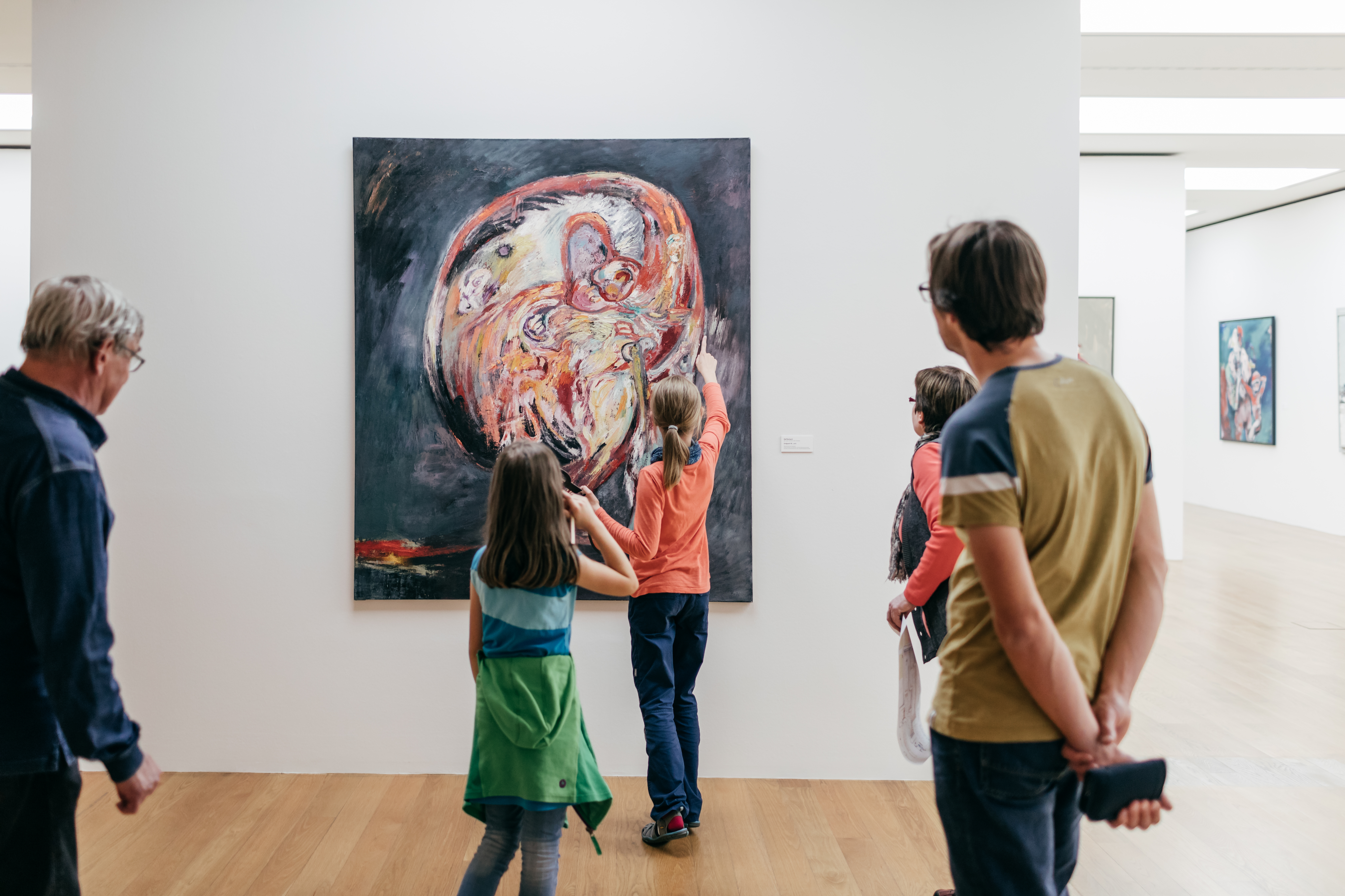 KI generiert: Das Bild zeigt eine Gruppe von Menschen in einem Kunstmuseum, die ein großes, abstraktes Gemälde betrachten. Die Szene betont die Interaktion der Besucher mit der Kunst.