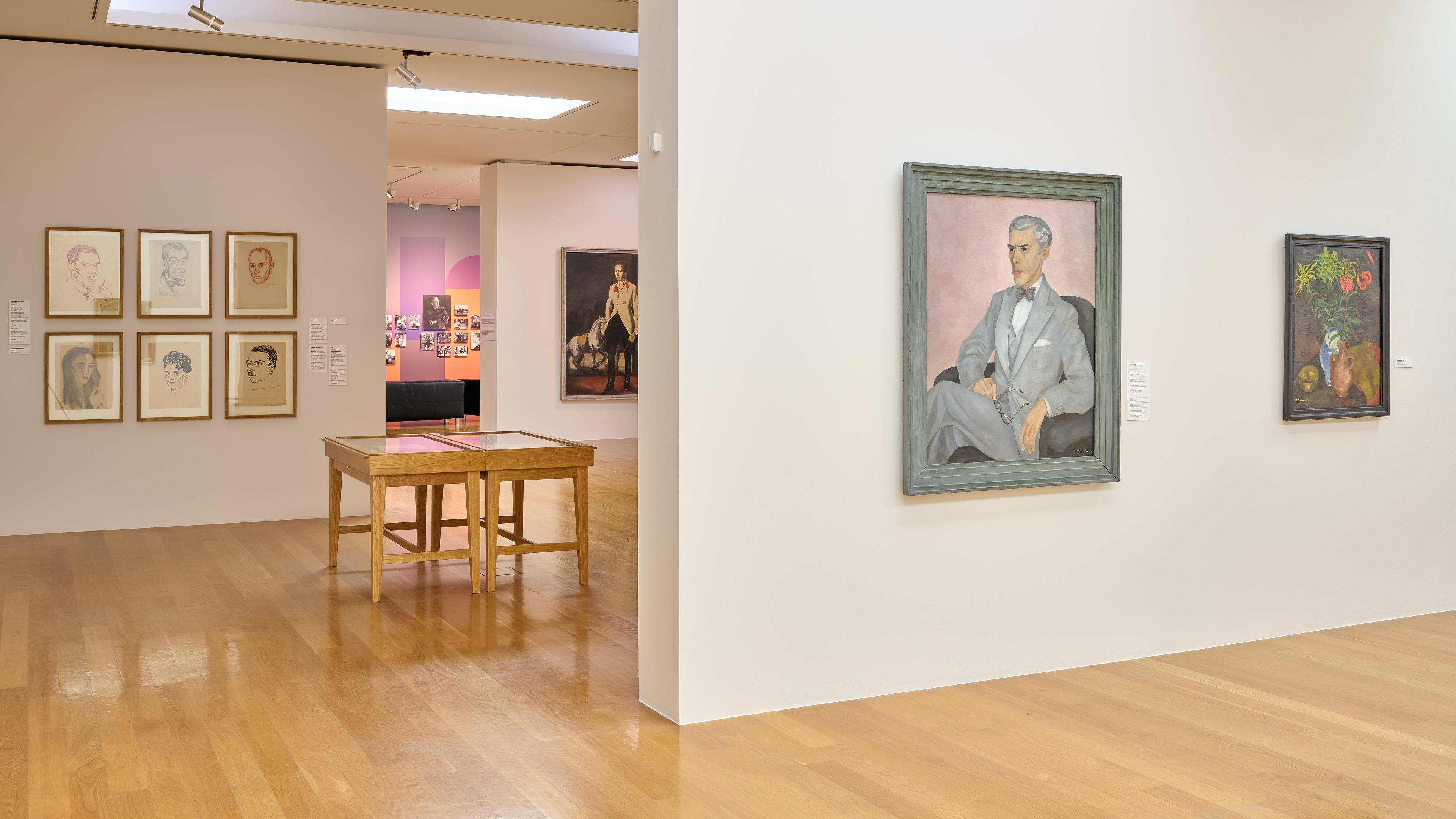 AI generated: The image shows the interior of an art gallery with several portraits on the walls. A painting in the centre shows a seated man in a suit, while other paintings and drawings hang on the surrounding walls.