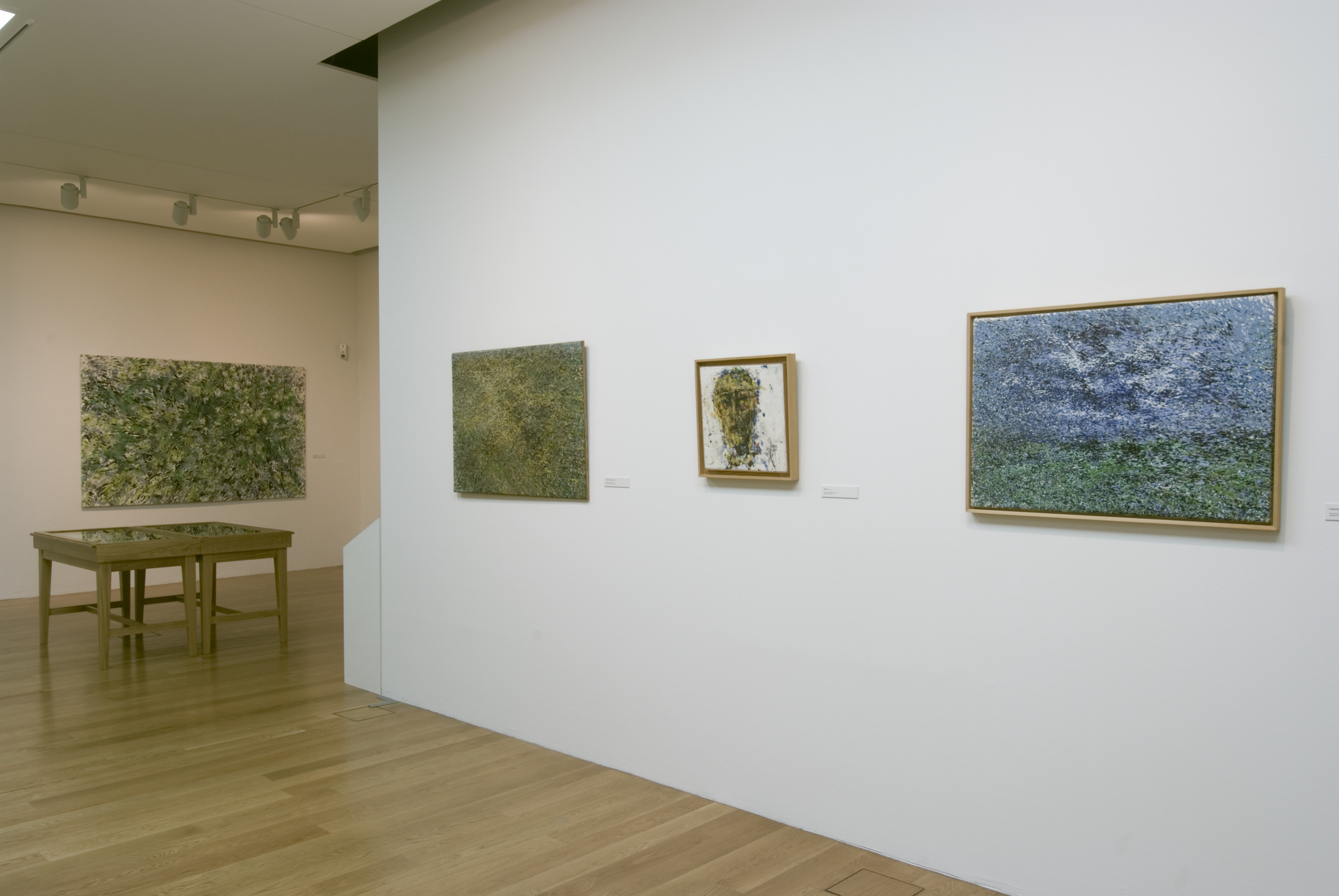 KI generiert: Das Bild zeigt einen Ausstellungsraum in einem Museum oder einer Galerie, in dem mehrere abstrakte Gemälde an den Wänden hängen. Der Raum ist minimalistisch eingerichtet und verfügt über eine Holzfläche.